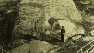 Old photo of a woman standing next to a giant stalagmite called the Liberty Bell in Marvel Cave at Silver Dollar City in Branson, Missouri, USA